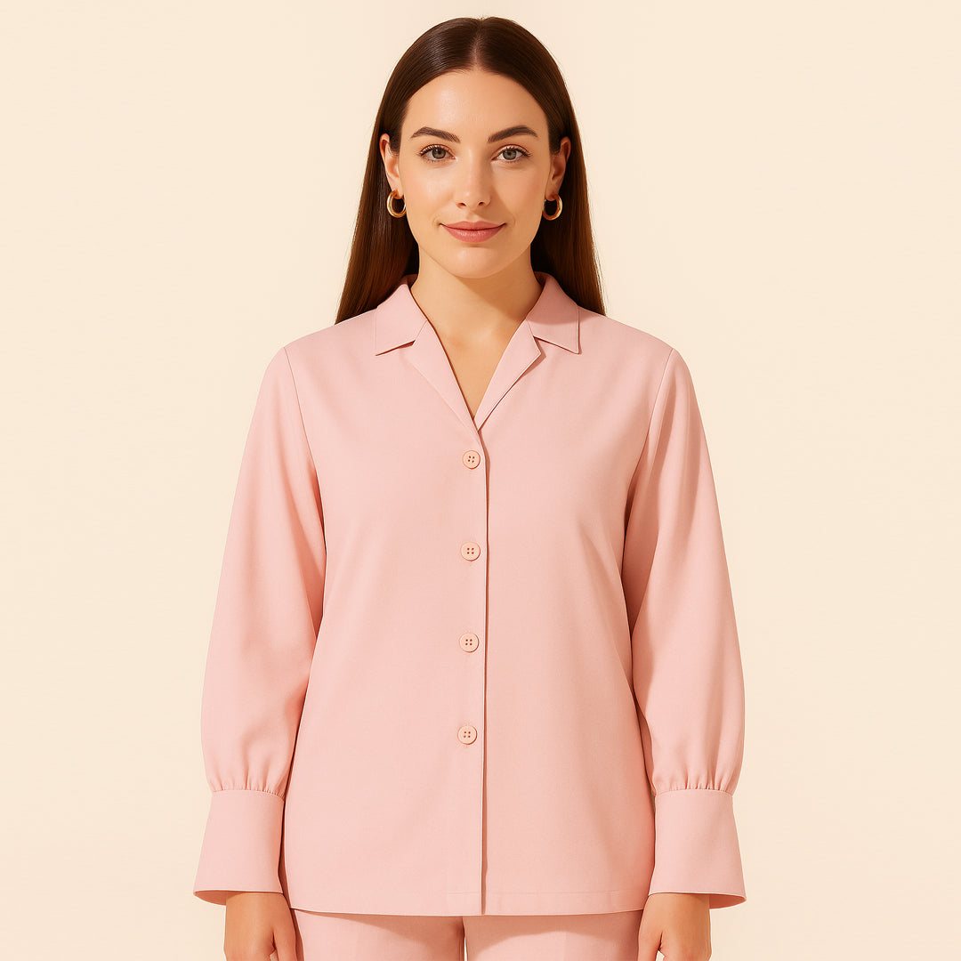 Woman wearing a light pink button-up long sleeve shirt with wide cuffs, studio background