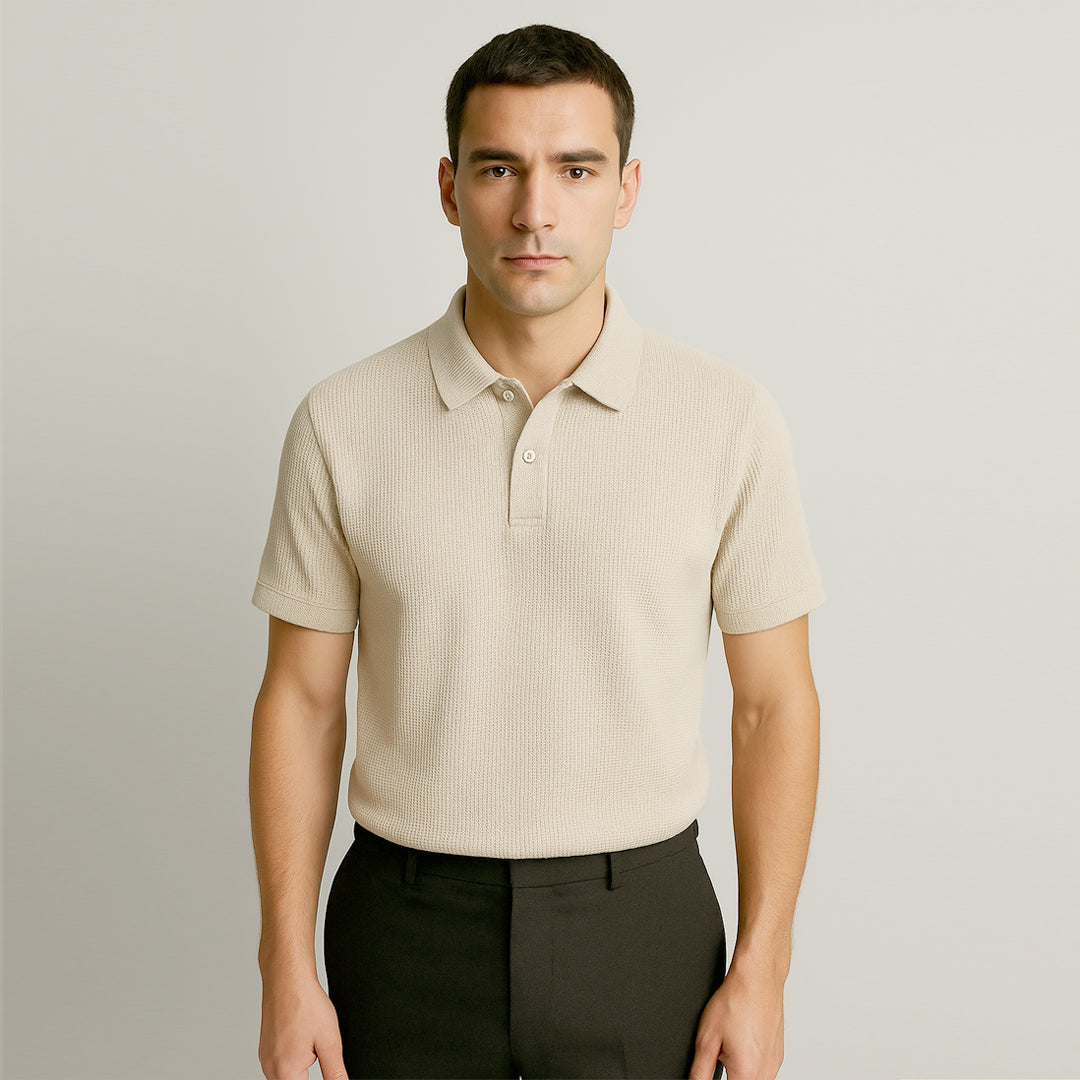 Man wearing a beige textured short sleeve polo shirt with black pants, neutral background