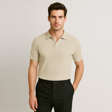 Man wearing short sleeve ivory textured polo shirt and black trousers, posing casually
