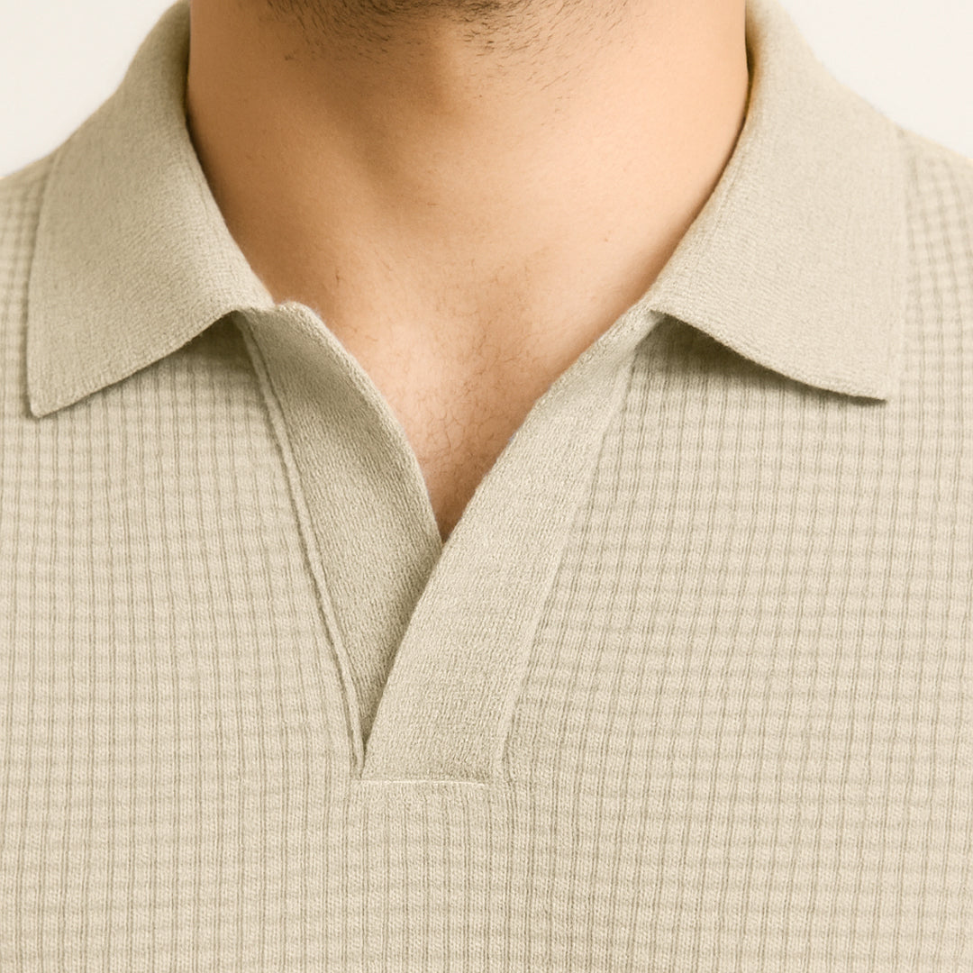 Close-up of a textured ivory waffle-knit polo shirt with a collar and open placket