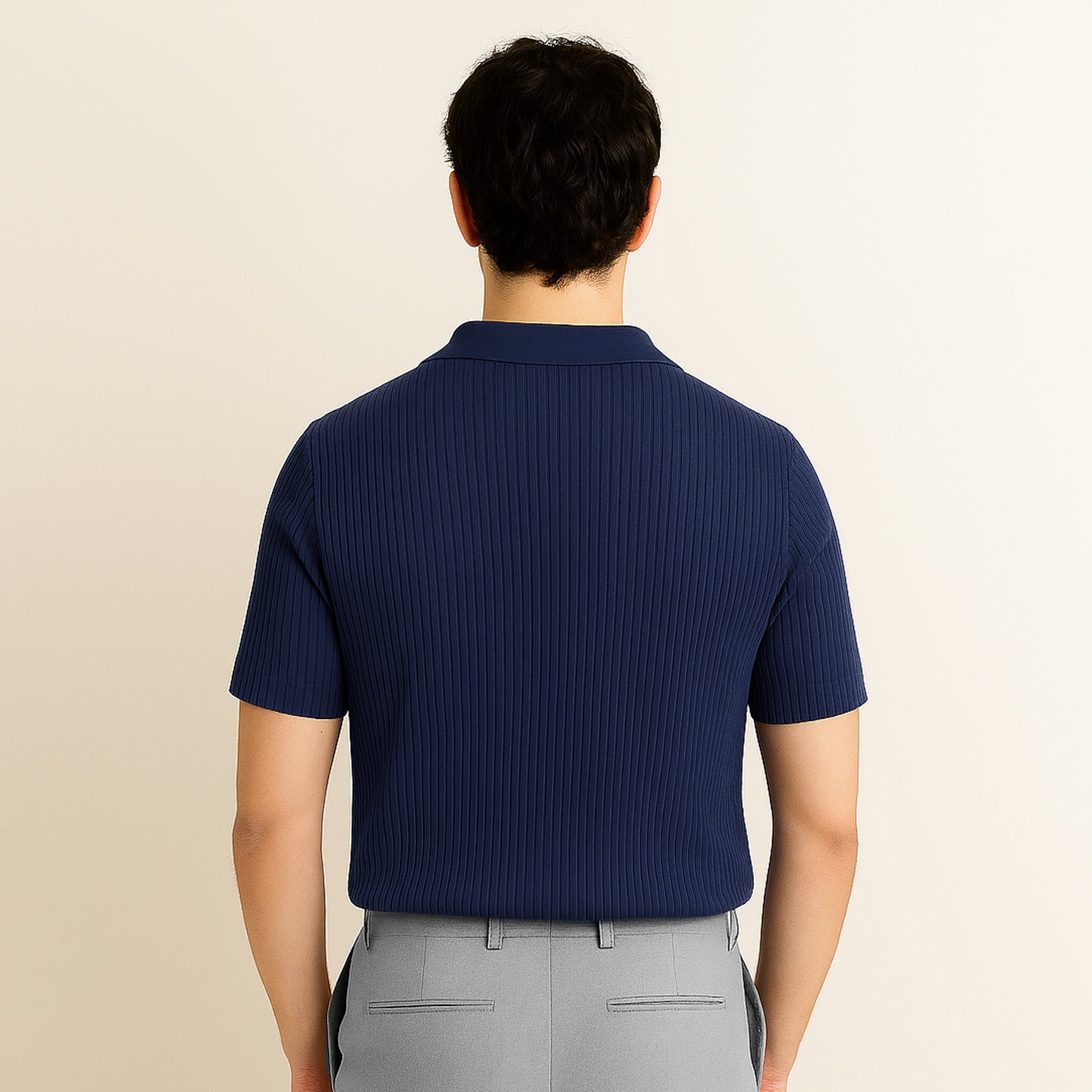 Back view of man wearing navy ribbed short-sleeve polo shirt and light grey pants