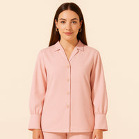 Woman wearing a light pink button-up long sleeve shirt with wide cuffs, studio background