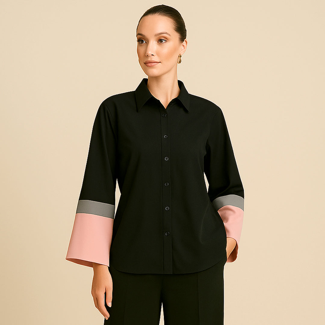 Woman wearing a black button-up shirt with wide pink and grey colorblock cuffs, paired with black pants