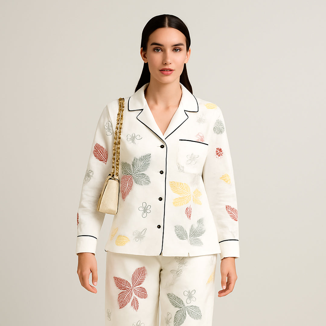 Woman wearing a white two-piece outfit with colorful leaf print and a gold chain shoulder bag.