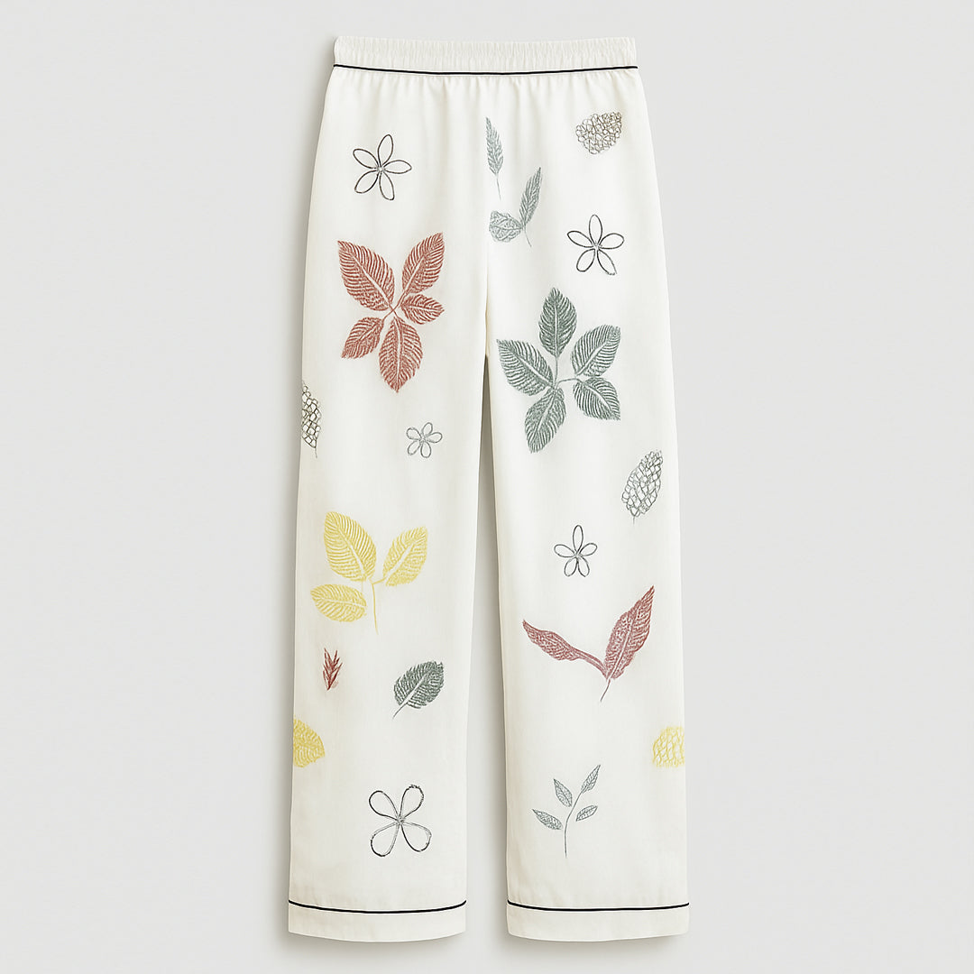 White women's pants with colorful leaf and floral print, relaxed fit, elastic waistband.
