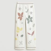 White women's pants with colorful leaf and floral print, relaxed fit, elastic waistband.