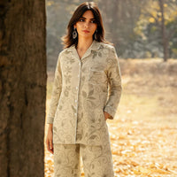 Woman wearing beige floral print button-up suit in outdoor autumn setting